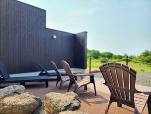 An outdoor seating area with lounge chairs and a table, surrounded by rocks. - Iwanai Kogen Hotel (Iwanai)