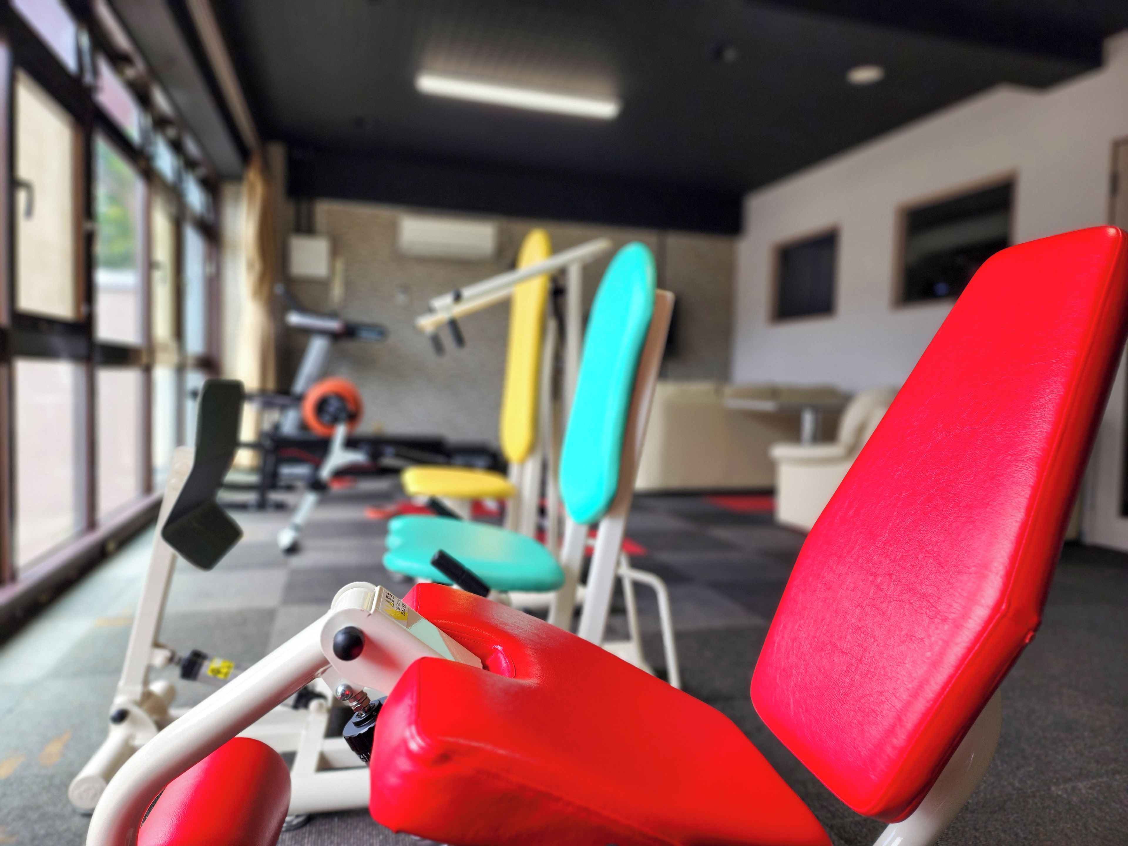 Une salle de sport équipée de matériel d’exercice et comprenant une chaise rouge.