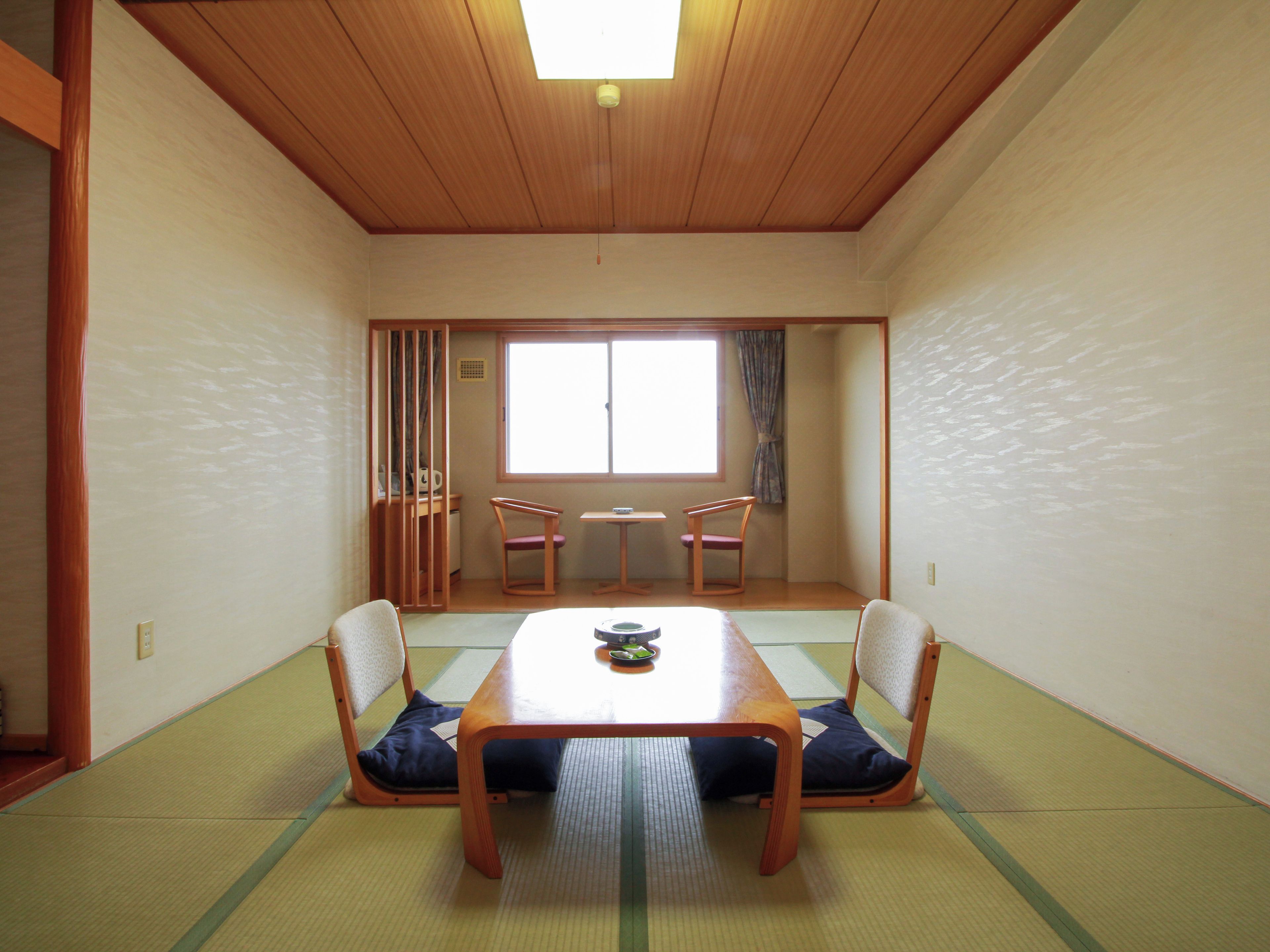 A traditional Japanese room with tatami flooring, a low table, and two chairs.
