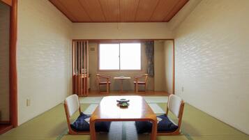 A traditional Japanese room with tatami flooring, a low table, and two chairs.
