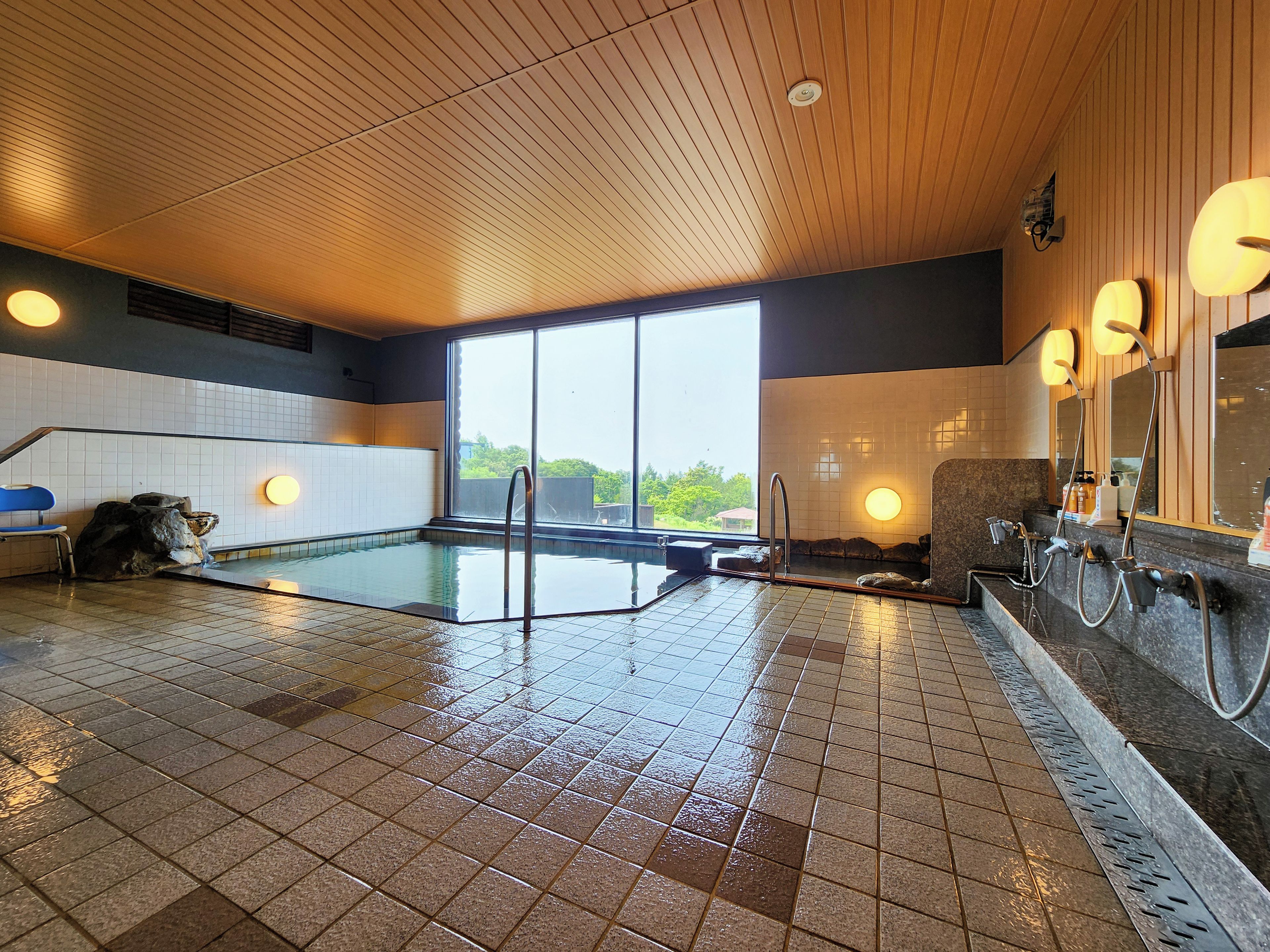 A swimming pool with a tiled floor, a wooden ceiling, and a large window.