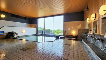 A swimming pool with a tiled floor, a wooden ceiling, and a large window.