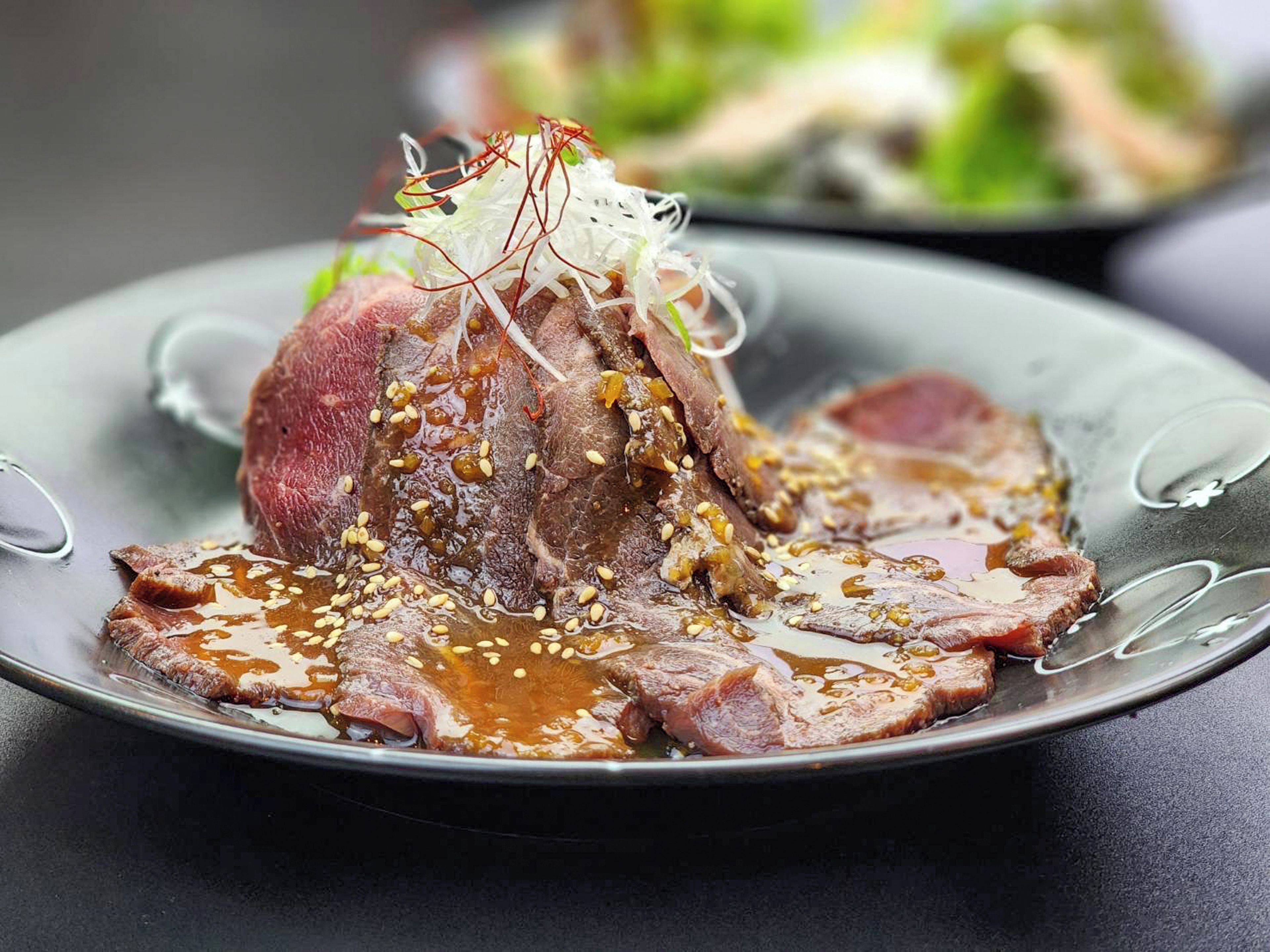 A plate with sliced meat and a decorative mound of vegetables.
