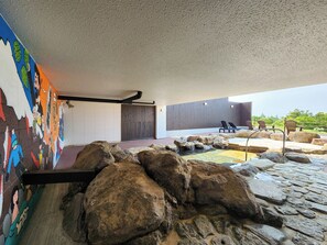 A modern interior with a stone water feature, a mural, and a seating area with lounge chairs. - Iwanai Kogen Hotel (Iwanai)