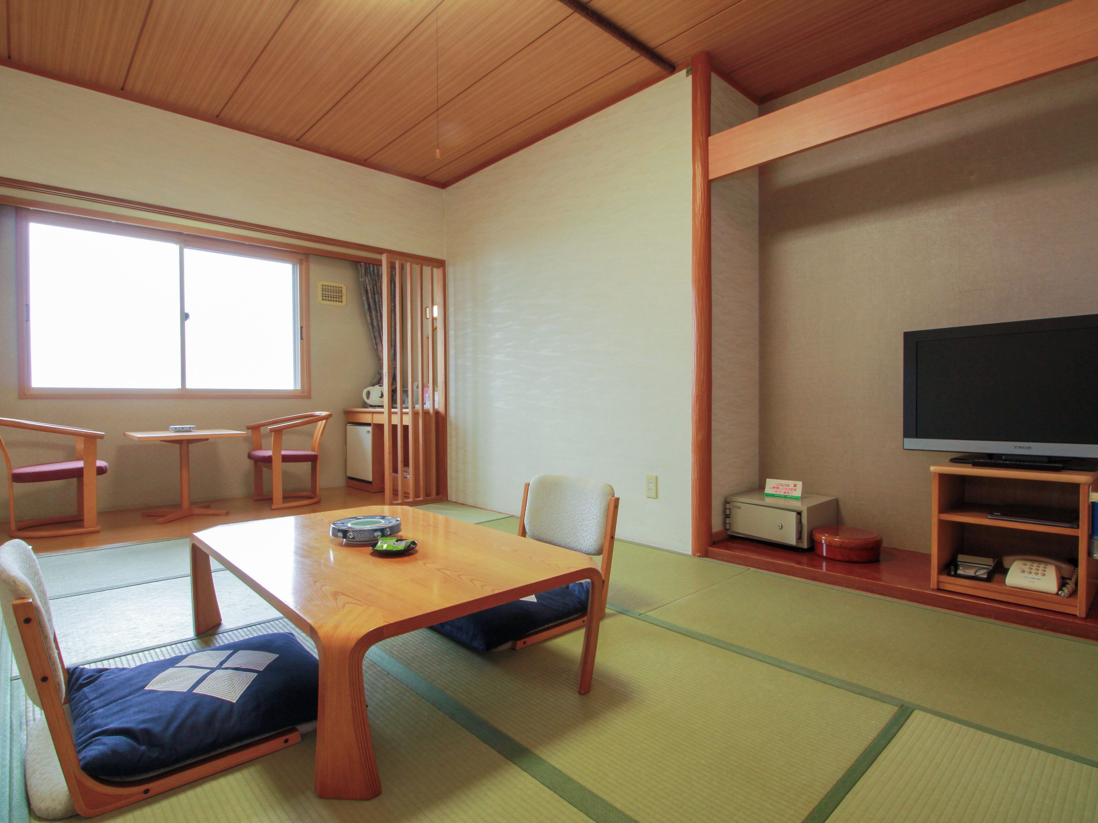 A traditional Japanese-style room with tatami flooring, a low table, and wooden furniture.