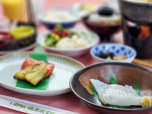 A table with various dishes, including a bowl of fish, a plate with a piece of grilled food, and a bowl of salad. - Iwanai Kogen Hotel (Iwanai)