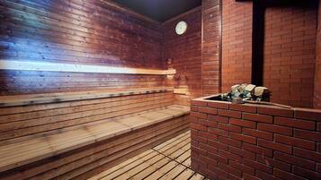 Una sauna con panche in legno e un muro in mattoni, un orologio e un braciere.