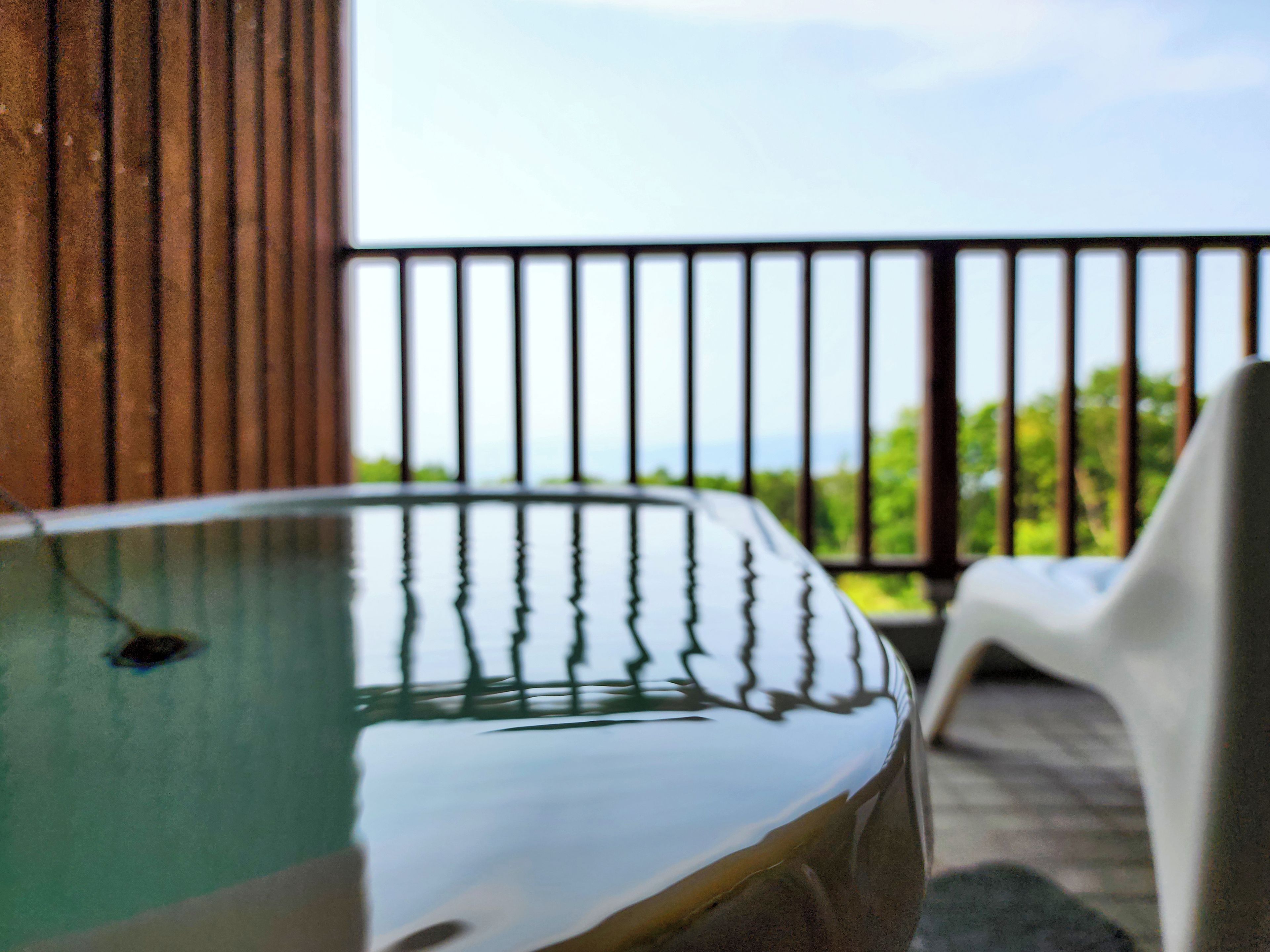 A hot tub with a view of greenery through a balcony railing.