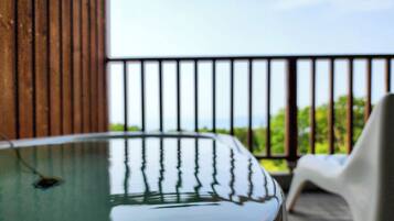 A hot tub with a view of greenery through a balcony railing.