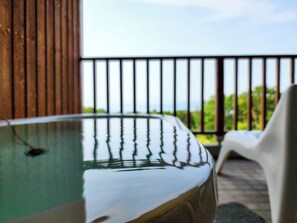 A hot tub with a view of greenery through a balcony railing. - Iwanai Kogen Hotel (Iwanai)