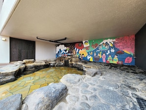 A stone hot spring area with a mosaic floor and a colorful mural on the wall. - Iwanai Kogen Hotel (Iwanai)
