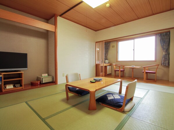 A traditional Japanese-style room with tatami flooring, a low wooden table, and a television. - Iwanai Kogen Hotel (Iwanai)