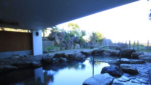 A stone-lined hot spring area with a wooden fence and rocks. - Iwanai Kogen Hotel (Iwanai)