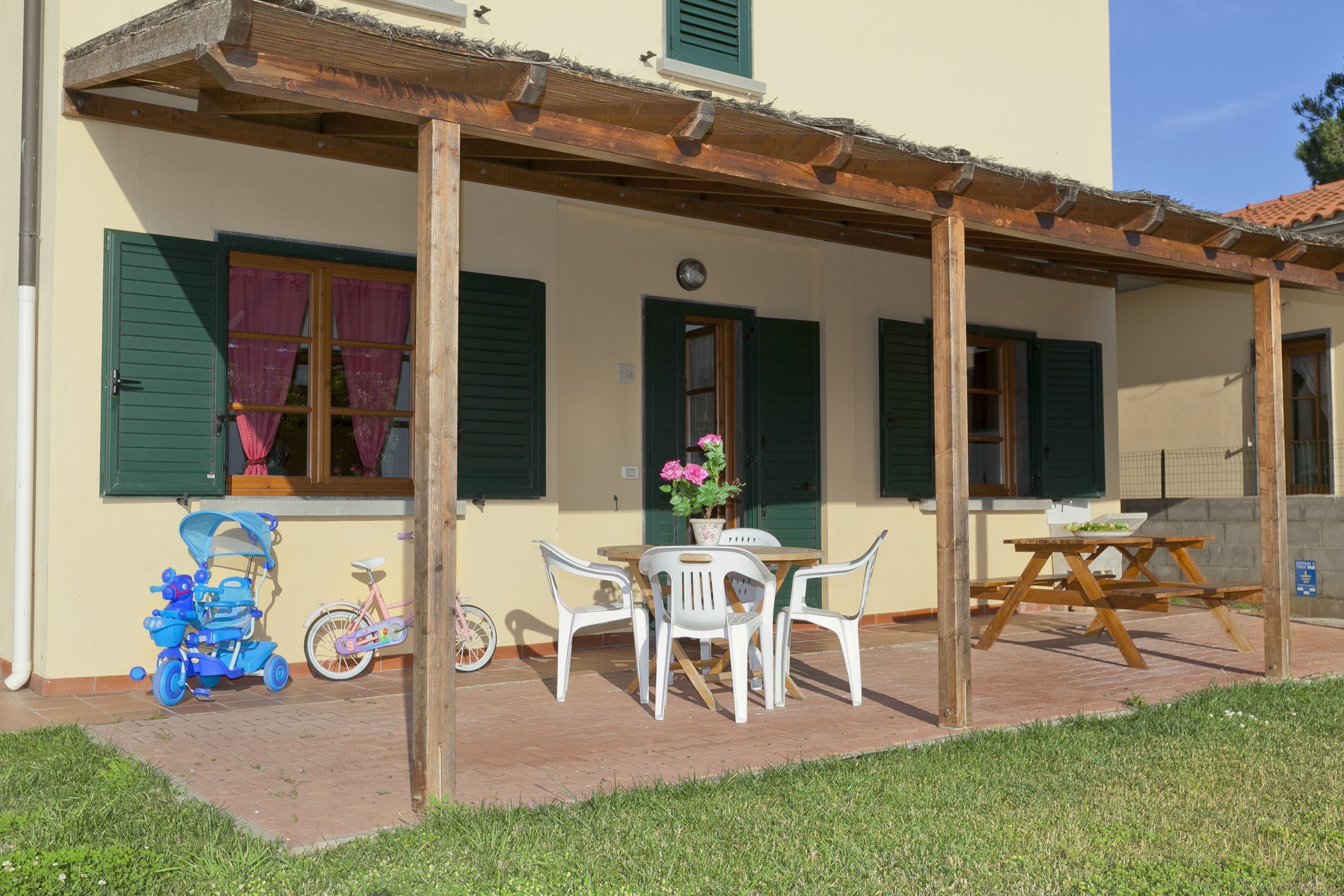 A covered patio with a table and chairs, a bicycle, and a stroller.
