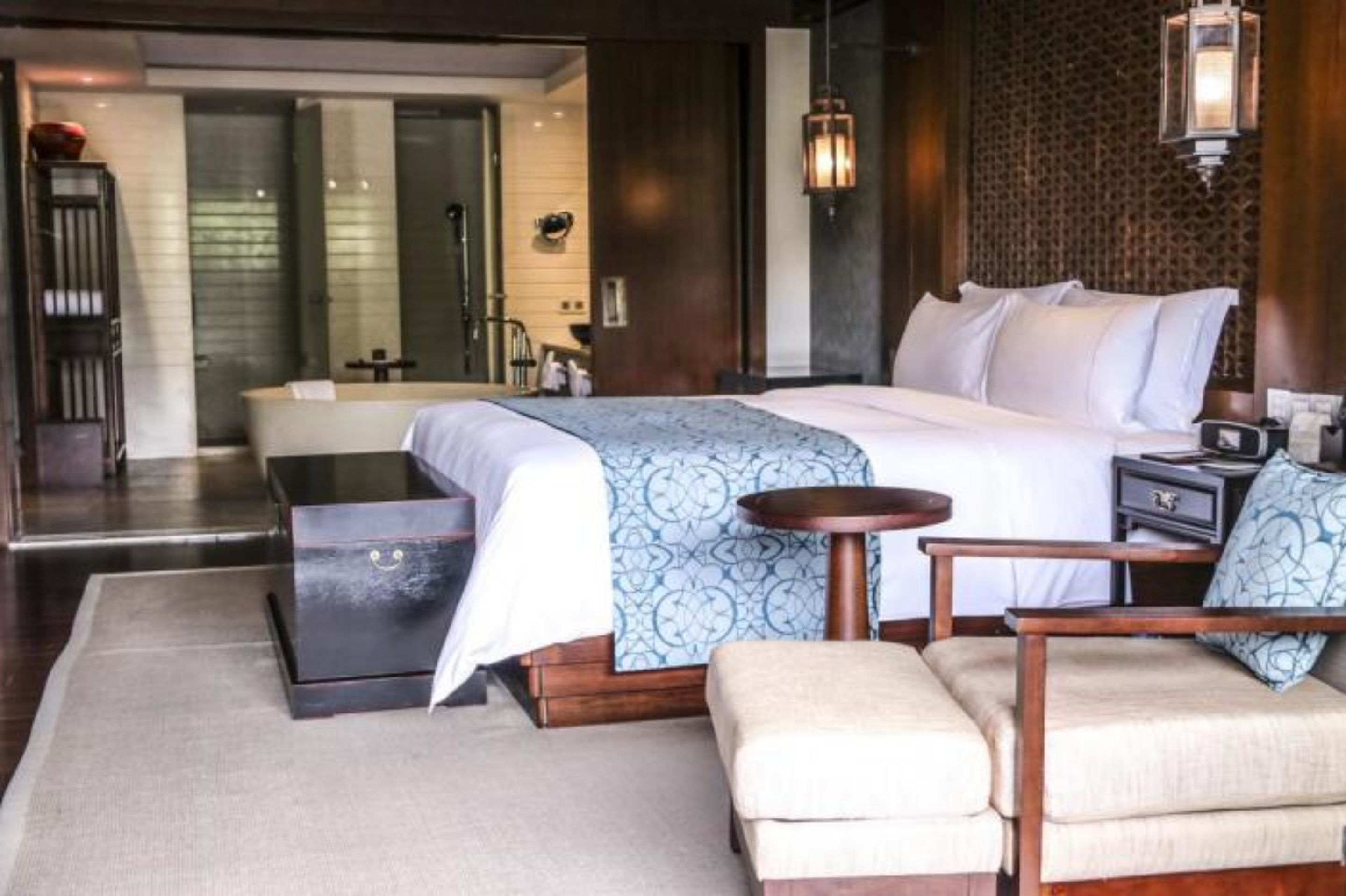 Una habitación de hotel moderna con una cama grande, una mesita redonda pequeña, un sofá y un aparador.