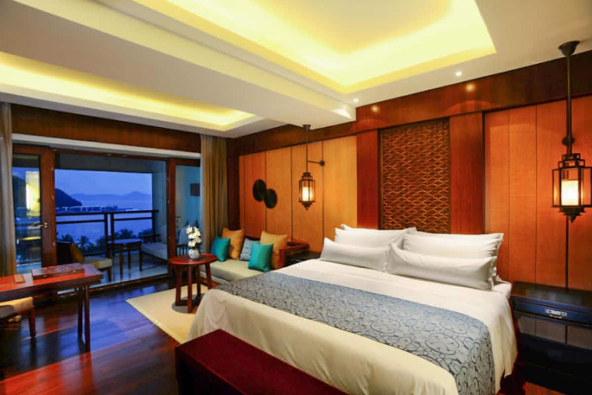 A hotel room with a large bed, a desk, and a view of the ocean.