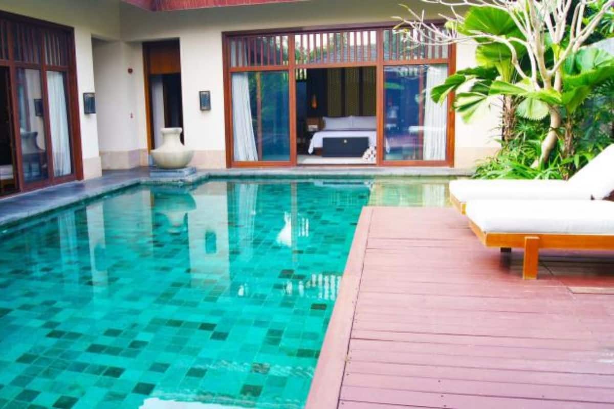 A swimming pool with a wooden deck and a lounge chair.