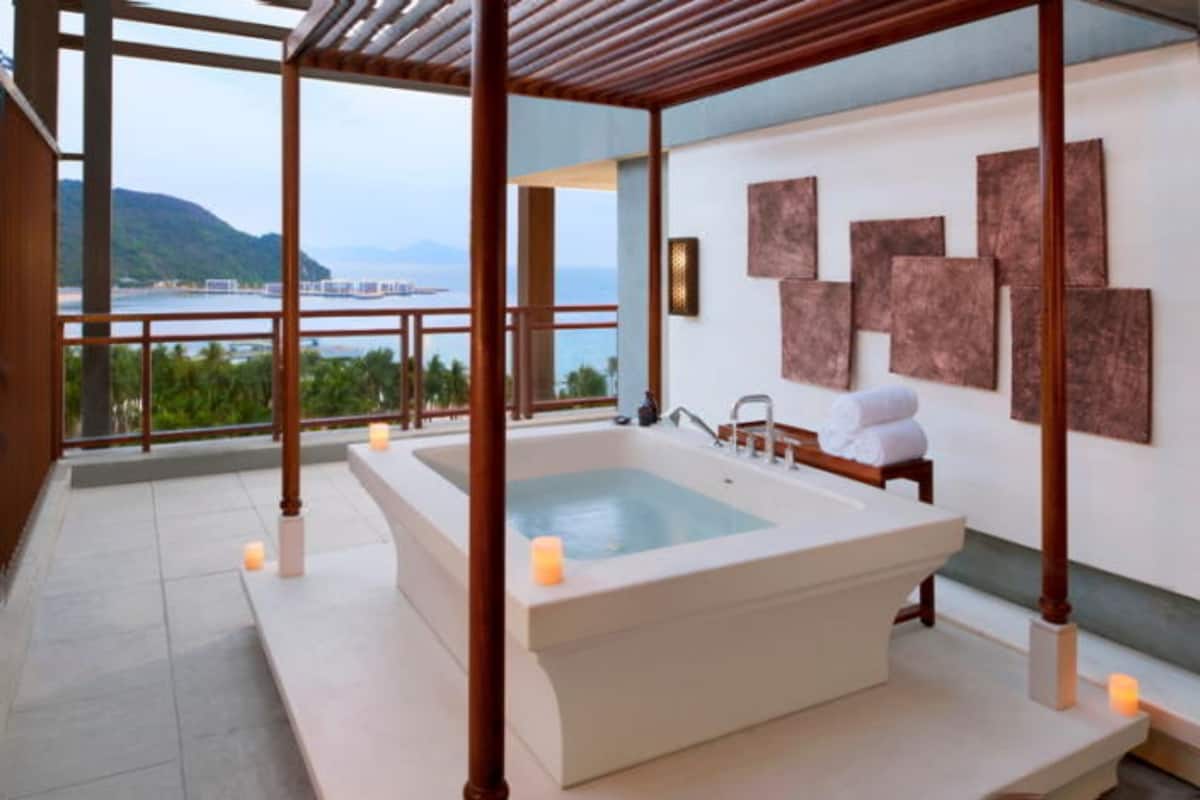 A spa area with a large bathtub, wooden pillars, and a view of the sea.