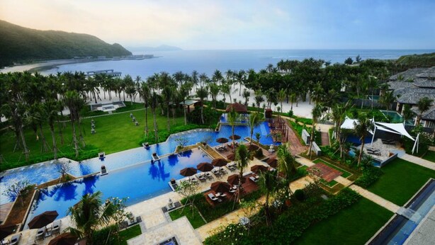 Ein Resort mit großem Pool, Palmen und Meerblick.