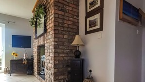 A living room with a stone fireplace, a television, a lamp, and a woven rug.