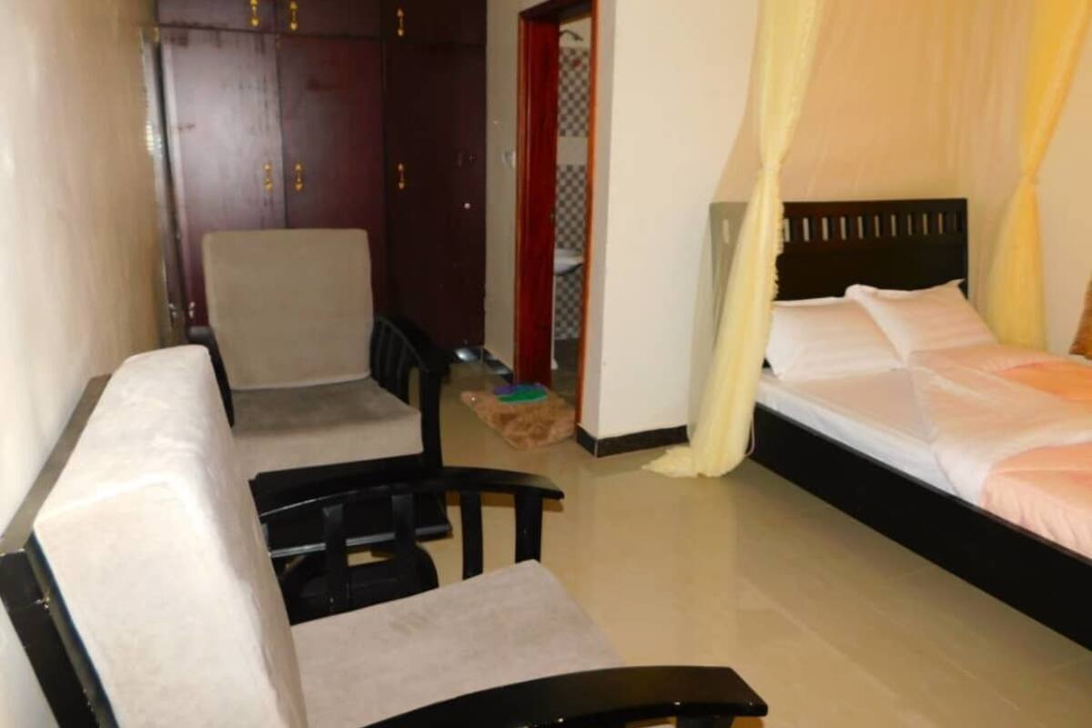 A bedroom with a bed, a chair, a wardrobe, and a small table.