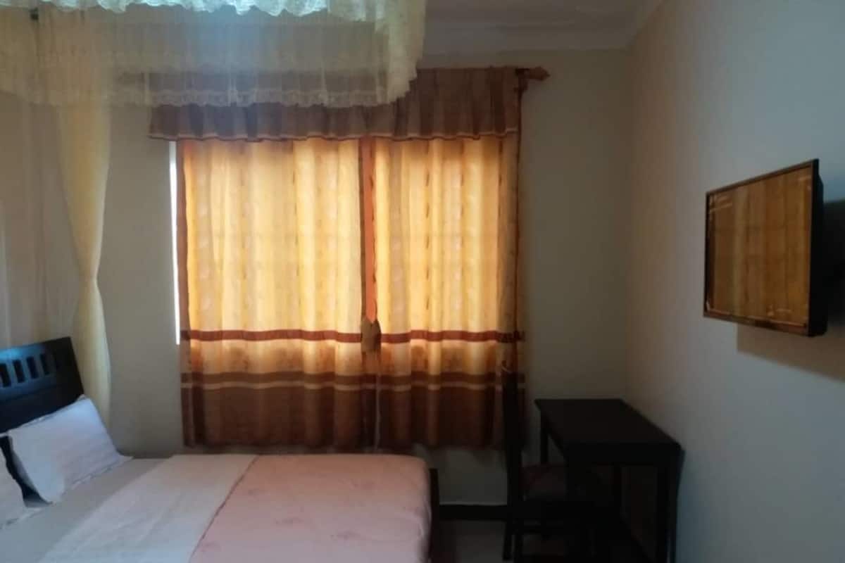A bedroom with a bed, a desk, and a chair.