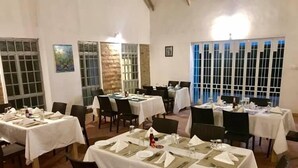 Un comedor con mesas dispuestas para varios invitados, con una mezcla de sillas y mesas de comedor.