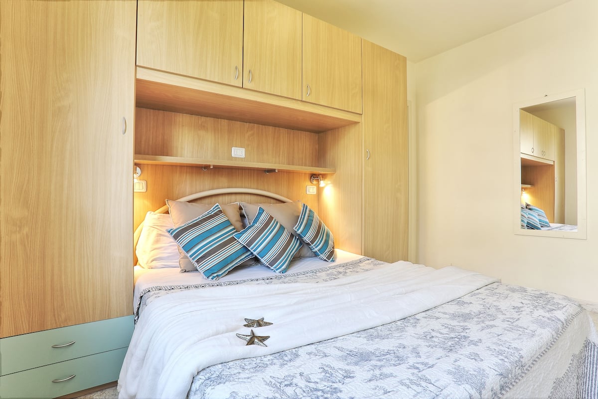 A bedroom with a bed, wooden wardrobe, and a mirror.