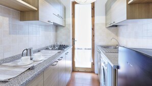 A modern kitchen with granite countertops, stainless steel appliances, and wooden cabinetry. - Case Sobrini (Rosignano Marittimo)