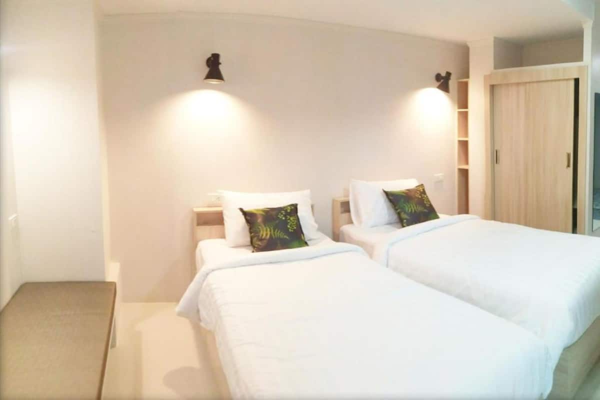 A hotel room with two beds, a small table, and a wardrobe.