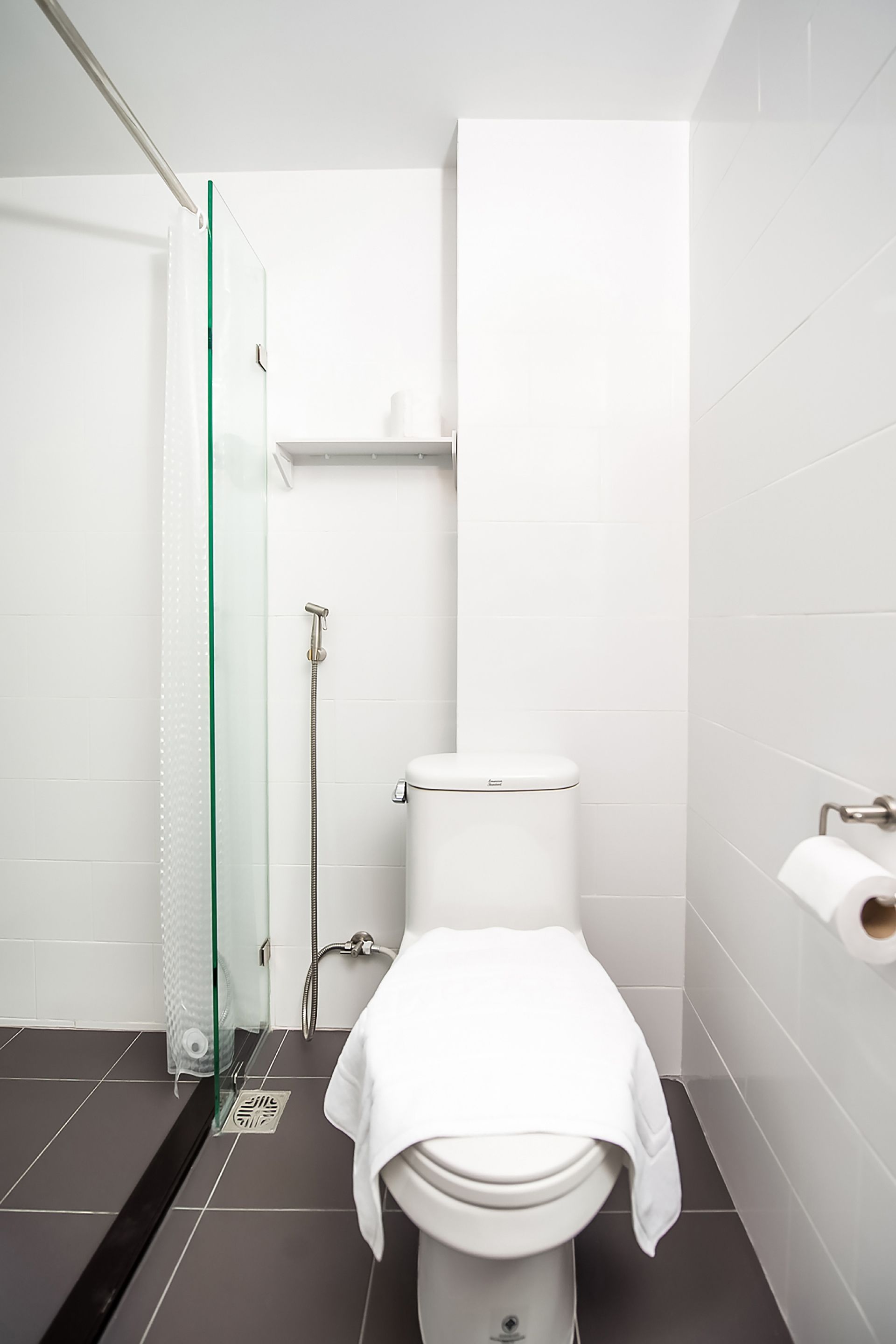A modern bathroom with a glass shower enclosure, a toilet, and a toilet paper holder.