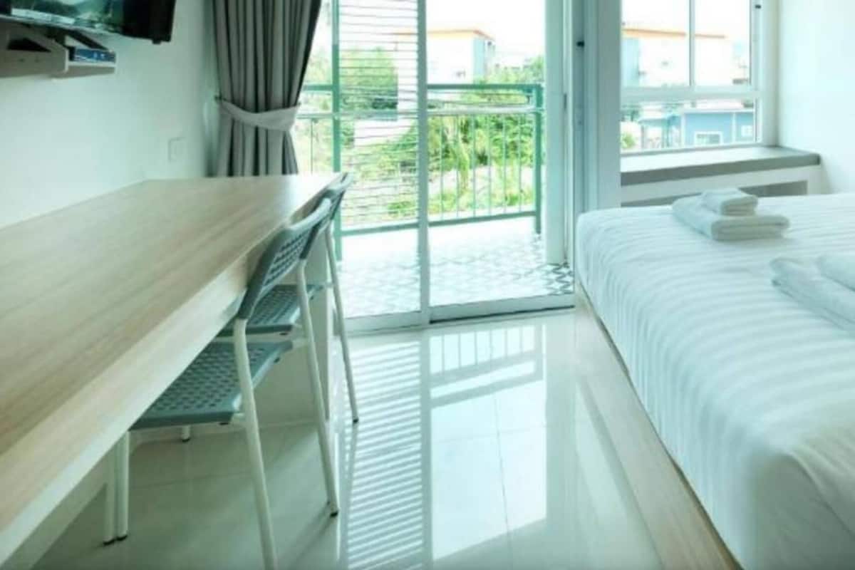 A hotel room with a bed, a desk, and a view of the outside.