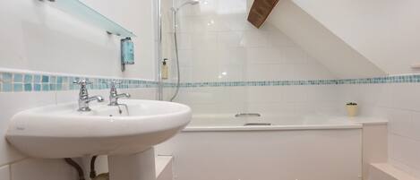 A modern bathroom with a white sink, a bathtub, and a shower enclosure.