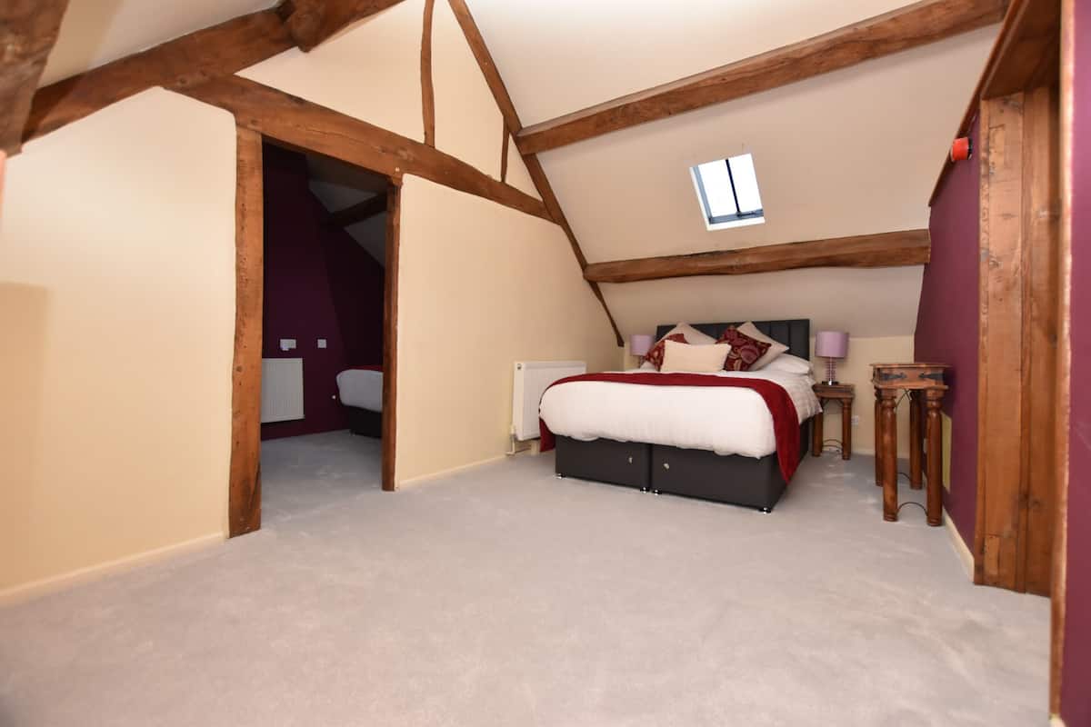 A bedroom with a bed, a nightstand, and a window.