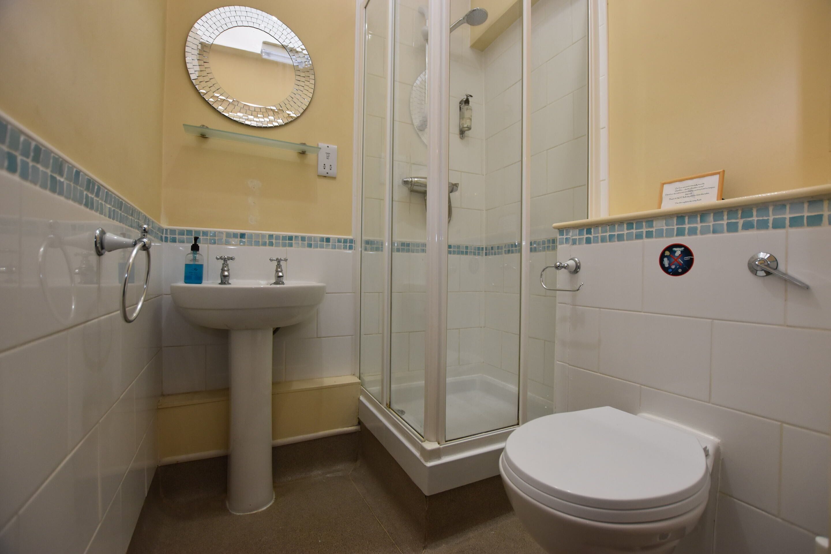 A bathroom with a glass-enclosed shower, a sink, and a toilet.