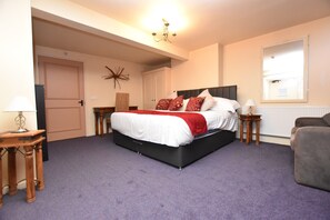 A bedroom with a large bed, a nightstand, a chair, and a door. - The Halford Bridge Inn (Shipston on Stour)