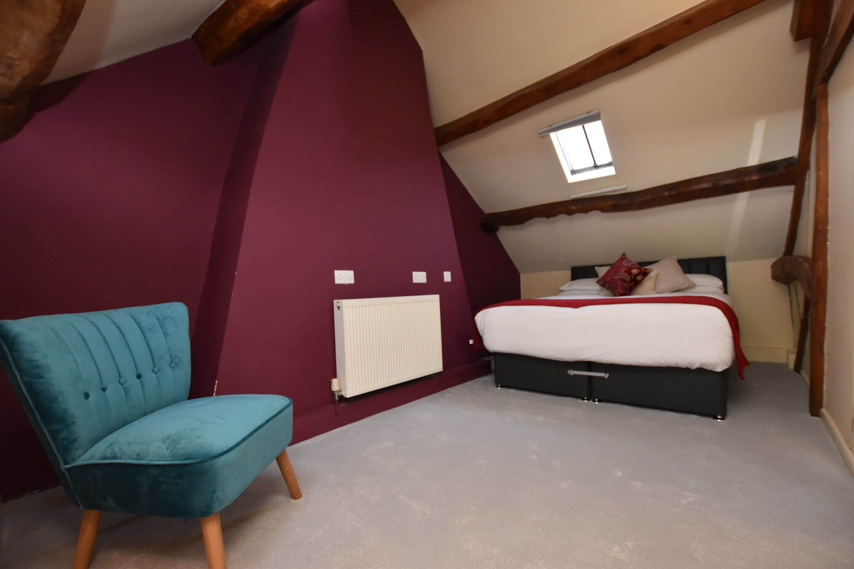 A bedroom with a bed, a chair, and a radiator.
