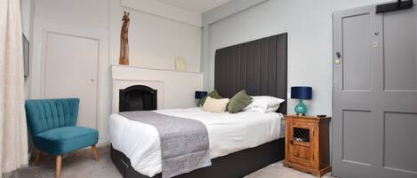 A bedroom with a bed, a chair, a nightstand, and a door.
