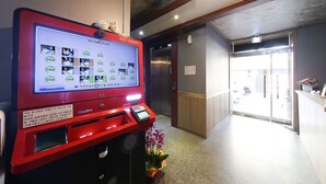 Un distributeur automatique rouge doté d’un écran numérique, situé dans le hall d’un hôtel.