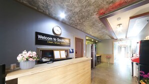Un espace d’accueil doté d’un comptoir en bois, d’une horloge et d’une enseigne qui souhaite la bienvenue aux clients de SooBIZTEL.