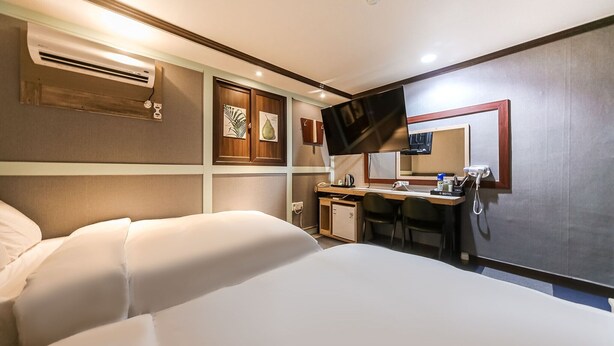 Une chambre d’hôtel équipée d’un lit, d’un bureau, d’une télévision et d’un mini-bar.