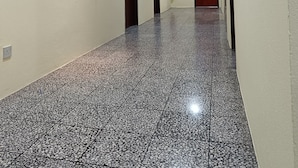 A hallway with a tiled floor, doors, a fire extinguisher, and a framed artwork on the wall.