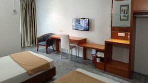 A hotel room with a bed, a desk, a chair, a television, and a wardrobe.