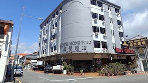 A multi-story hotel with a curved facade, air conditioning units, and a sign for 'Hotel Hong Ping' and 'Wild Chilies' restaurant.