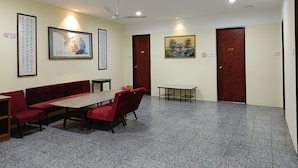 A conference room with a long table, red chairs, a ceiling fan, and artwork on the walls.