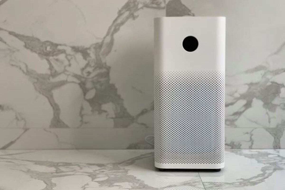 A white, rectangular device with a perforated front and a circular cutout on the top, placed on a marble-patterned surface.