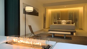 A modern hotel room with a bed, bedside table, lamp, chair, and a fireplace. - K Maison Lanna Boutique Hotel (Chiang Mai)