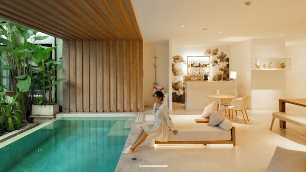 A modern indoor pool area with a seating area, a bar, and a large plant. - K Maison Lanna Boutique Hotel (Chiang Mai)