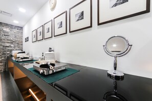A reception area with a black counter, framed pictures on the wall, a clock, and a mirror. - Browndot Hotel - Gold (Busan)