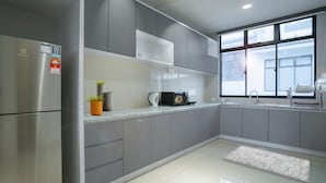 A modern kitchen with grey cabinets, a stainless steel refrigerator, a sink, and a window providing natural light.